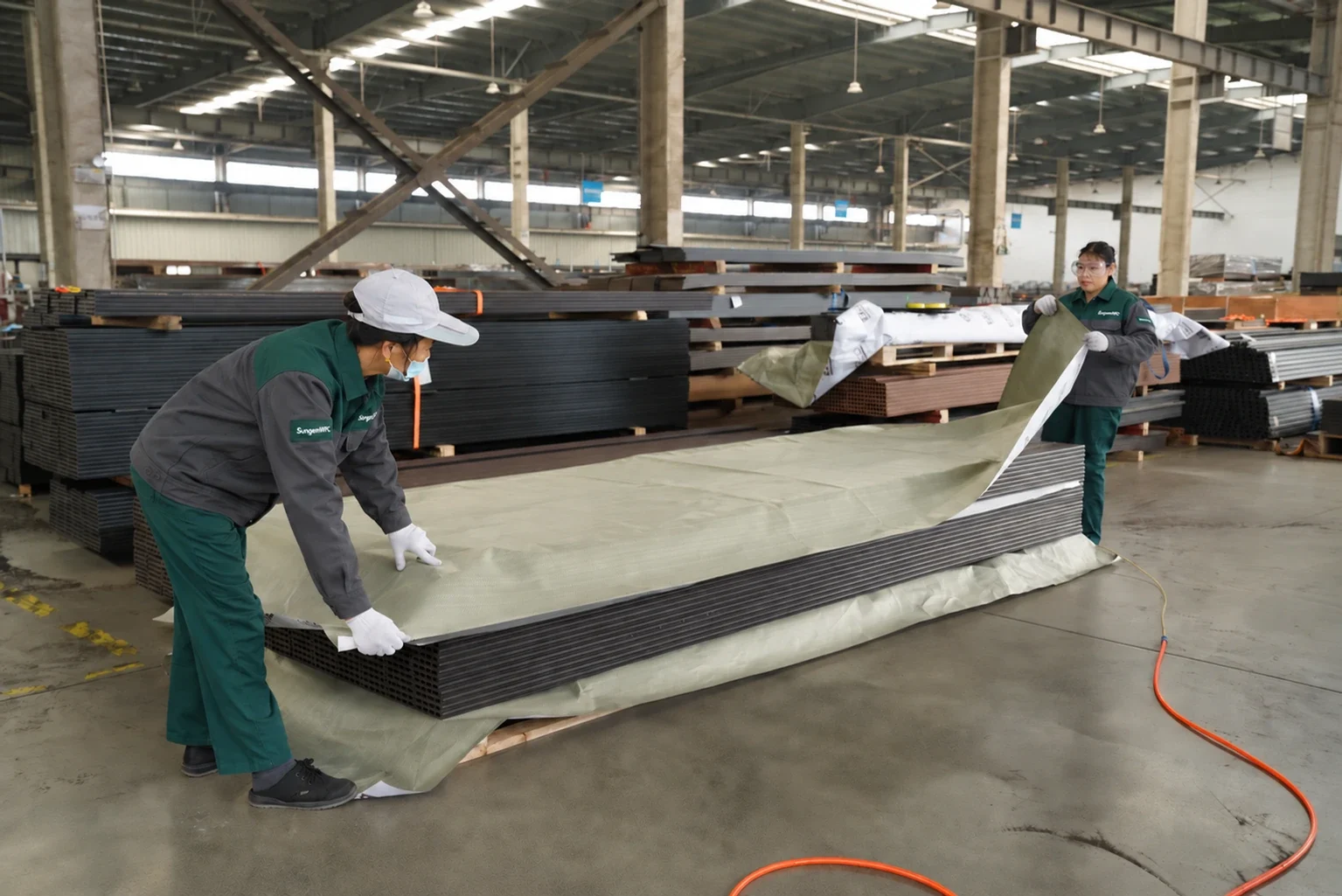Workers wrapping a stack of composite boards for packing